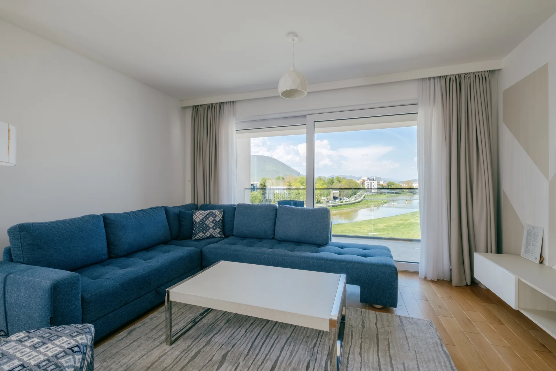 Blue corner living room with dining area and windows looking towards the river