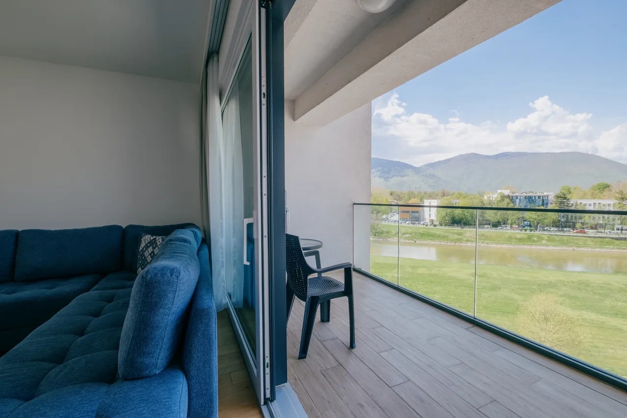 Balcony — Two-bedroom apartment. Blue corner sofa and grey kitchen